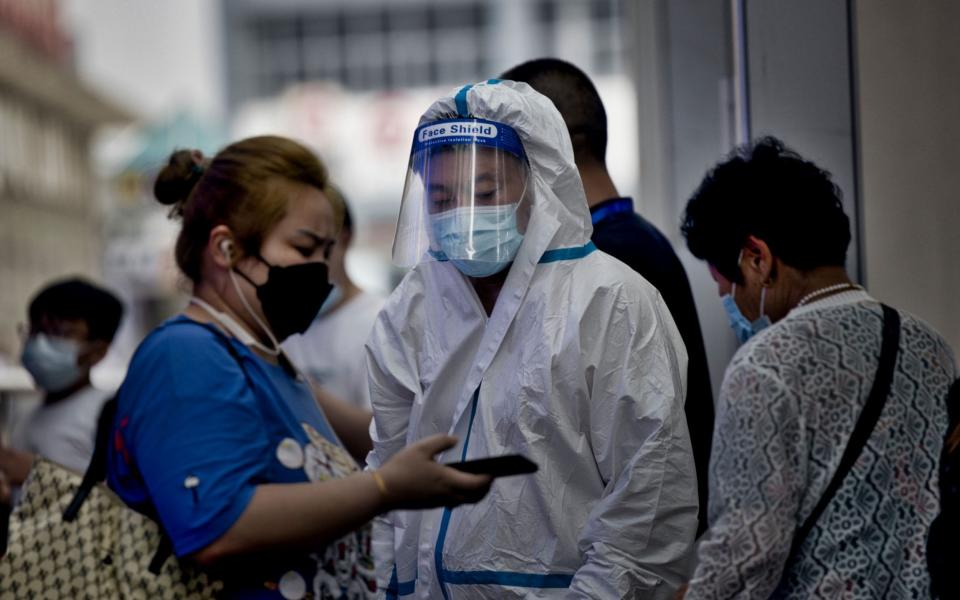 A traveler shows a health code on a smartphone to a medical personnel at the railway station in Shanghai, China, 29 July 2021. China reported 24 new locally transmitted COVID-19 cases, according to the National Health Commission. More than 170 people have been diagnosed with the Delta variant. The main outbreak is in the eastern city of Nanjing, in Jiangsu province. - Shutterstock