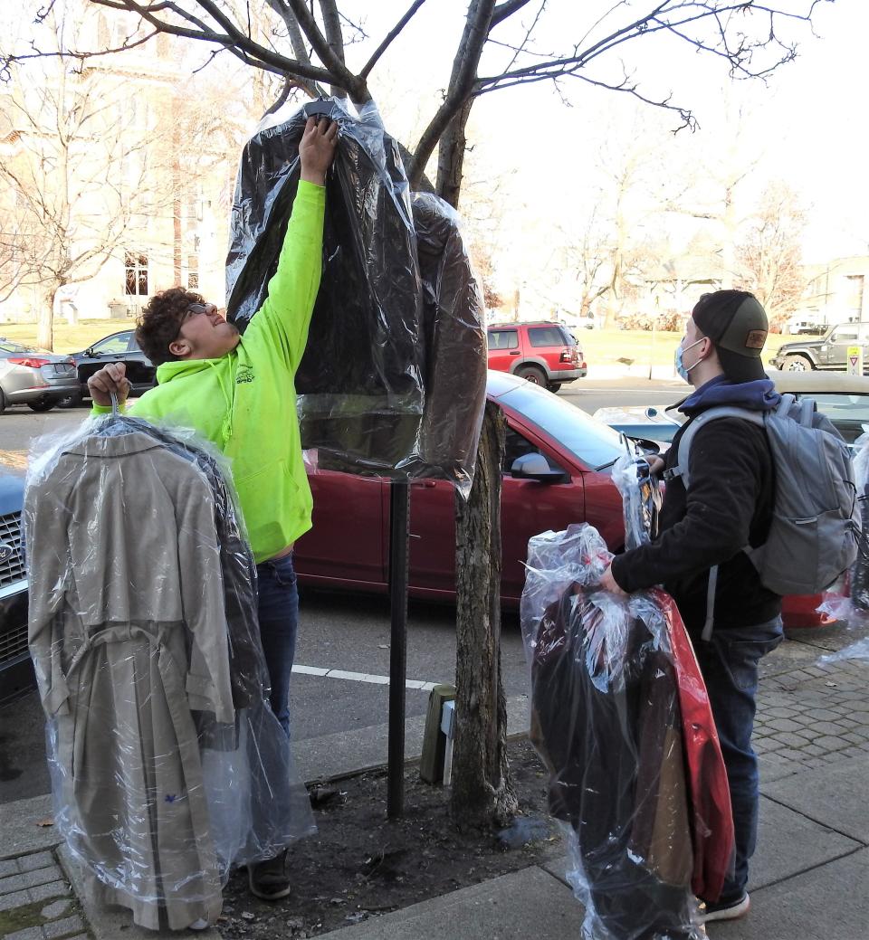 Students Dyson Mossholder and Mat Colbird of the Coshocton Opportunity School hang coats on trees along Main Street as part of the 2021 Dress Up Coshocton clothing drive. Students also placed items such as socks, gloves, hats and scarves in the pockets of the coats for people who needed winter clothes.
