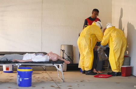 Centers for Disease Control and Prevention (CDC) instructor Satish Pillai (back) gives guidance on the protocol for drawing blood to health care workers in preparation for the response to the current Ebola outbreak, during a CDC safety training course in Anniston, Alabama, October 6, 2014. REUTERS/Tami Chappell