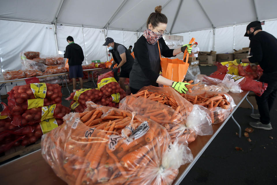 FILE - In this April 18, 2020, file photo, San Francisco-Marin Food Bank volunteers pack food into bags to be delivered to people in San Francisco. About 25 million Americans will be eligible for more food assistance money under a new policy adopted by President Joe Biden's administration under a change announced Thursday, April 1, 2021. (AP Photo/Jeff Chiu, File)