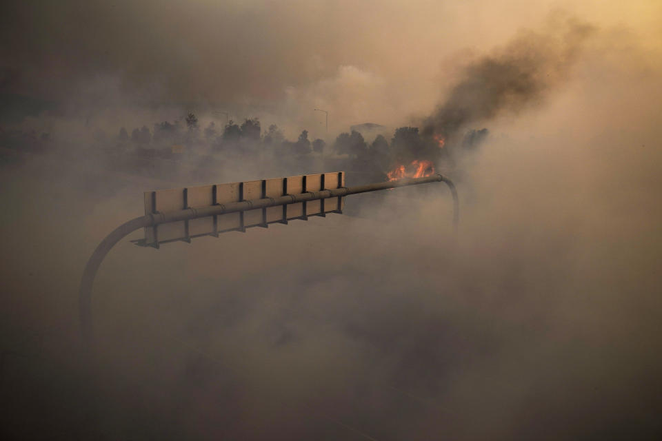 Smoke from the Silverado Fire fills the air along the 241 State Highway Monday, Oct. 26, 2020, in Irvine, Calif. A fast-moving wildfire forced evacuation orders for 60,000 people in Southern California on Monday as powerful winds across the state prompted power to be cut to hundreds of thousands to prevent utility equipment from sparking new blazes. (AP Photo/Jae C. Hong)