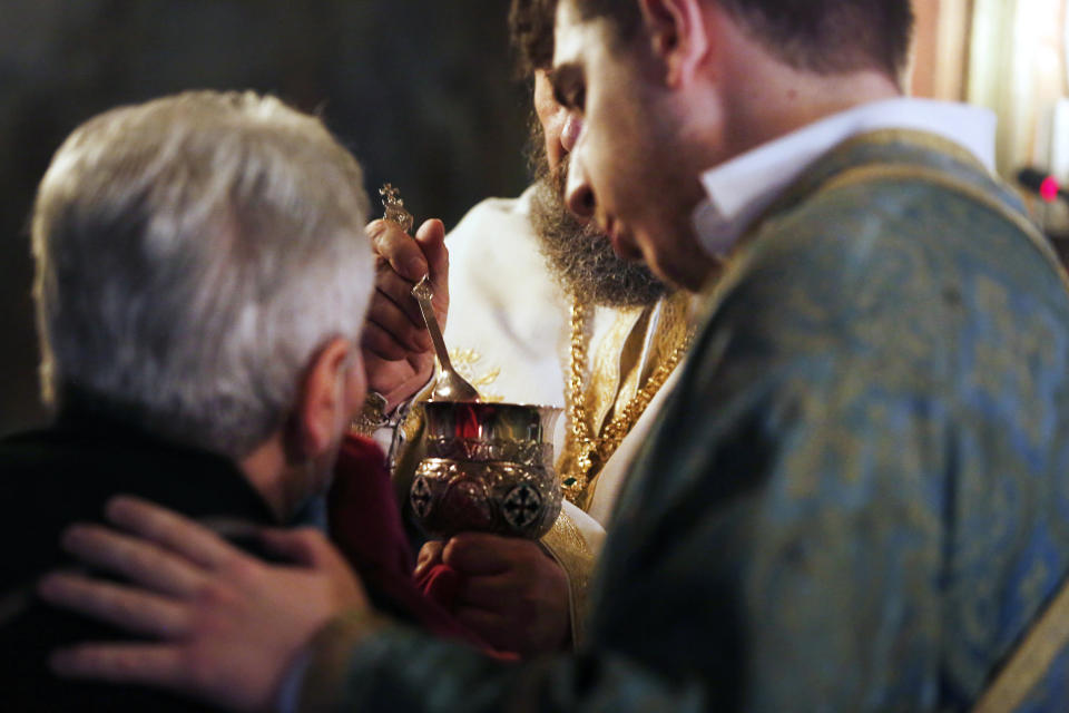 In this Sunday, May 24, 2020, photo, a Greek Orthodox priest uses a traditional shared spoon to distribute Holy Communion during Sunday Mass in the northern city of Thessaloniki, Greece. Contrary to science, the Greek Orthodox Church says it is impossible for any disease, including the coronavirus, to be transmitted through Holy Communion. (AP Photo/Giannis Papanikos)