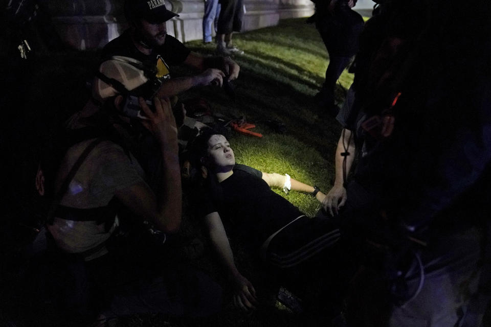 A protester lies injured during clashes with police outside the Kenosha County Courthouse late Tuesday, Aug. 25, 2020, in Kenosha, Wis. Protests continue following the police shooting of Jacob Blake two days earlier. (AP Photo/David Goldman)
