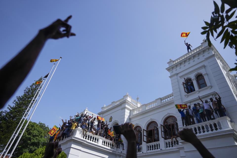 A Sri Lankan protester waves the national flag from the rooftop of Sri Lankan Prime Minister Ranil Wickremesinghe's office, demanding he resign after president Gotabaya Rajapaksa fled the country amid economic crisis in Colombo, Sri Lanka, July 13, 2022. The image was part of a series of images by Associated Press photographers that was a finalist for the 2023 Pulitzer Prize for Breaking News Photography. (AP Photo/Eranga Jayawardena)