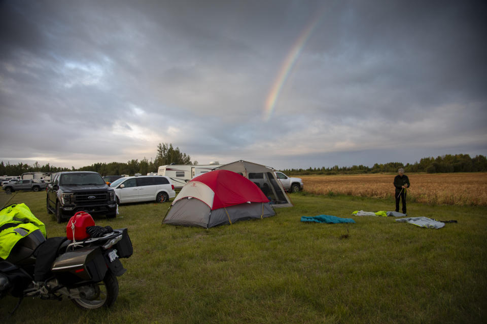 Craig Yeo, an evacuee from Yellowknife, territorial capital of the Northwest Territories, packs up his tent under a rainbow at a free campsite provided by the community in High Level, Alta., Thursday, Aug. 17, 2023. (Bill Braden /The Canadian Press via AP)