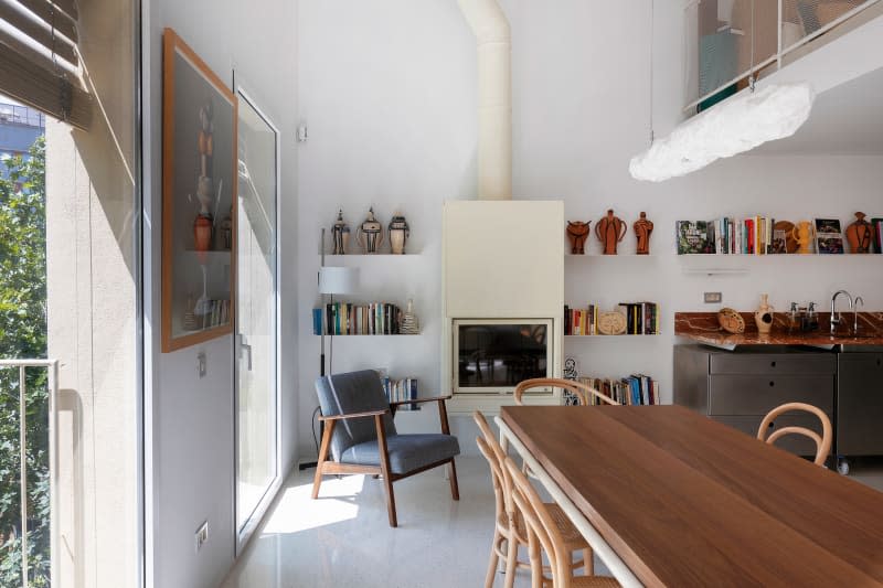 Large white dining room with large wood table, fireplace,  and kitchen in the background