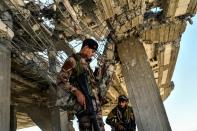 Members of the Syrian Democratic Forces walk on a ravaged building near Raqa's central hospital on October 16, 2017