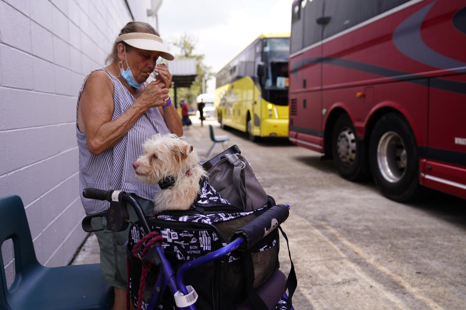 Vicki Veitch prepares to board a bus at the shelter with her dog Shilo in the aftermath of Hurricane Ida, Friday, Sept. 3, 2021, in Jefferson Parish, La. (AP Photo/Matt Slocum)