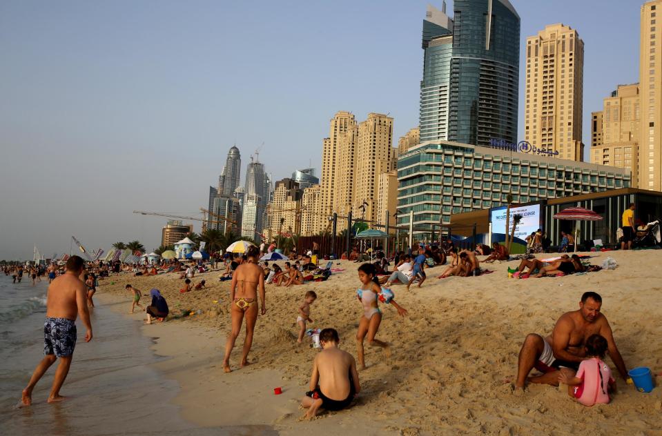 In this Saturday, April 19, 2014 photo, people enjoy the beach in Dubai, United Arab Emirates. The ribbon of beach nestled along the towering skyscrapers rising from Dubai’s man-made marina district is a rare spot in the Middle East, bringing together the conservatively dressed and the bikini-clad in a multiethnic mix of those with means and those still striving for a more comfortable life. The Princess tower is seen at background left. (AP Photo/Kamran Jebreili)