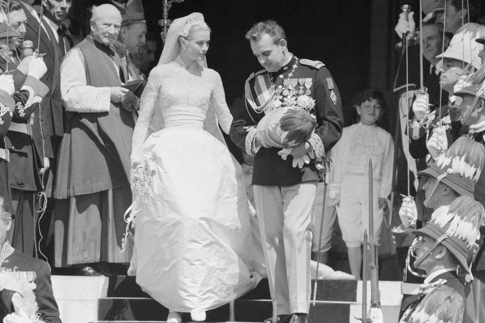 <p>Bettmann</p> Grace Kelly and Prince Rainier of Monaco waving to the crowds from the Monaco Royal Palace after their wedding in the Cathedral of St. Nicholas.