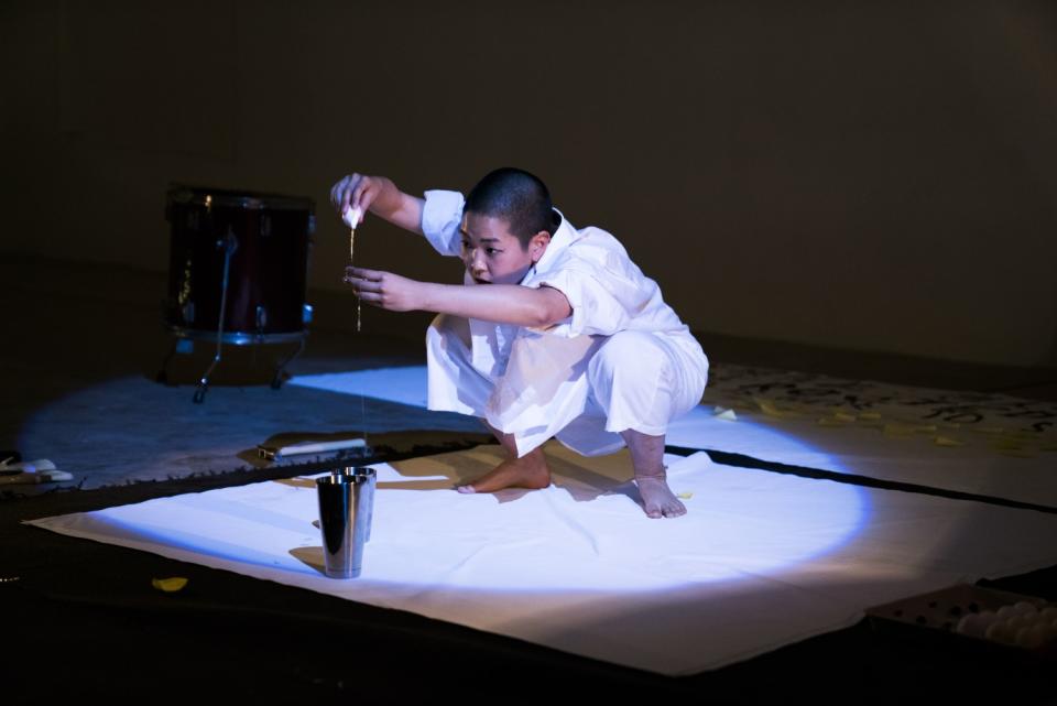 Kyoko Takenaka pours yolk out of an egg as part of a "Home" live performance.