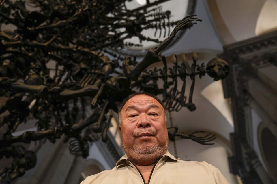 Chinese artist Ai Weiwei poses in front of his unveil glass body of work 'La Commedia Umana' a huge hanging glass sculpture otherwise referred to as a 'chandelier' at the San Giorgio deconsecrated church in Venice, Italy, Friday, Aug. 26, 2022. Chinese artist Ai Weiwei lampoons the surveillance culture and social media with his first ever glass sculpture, made on the Venetian island of Murano, that stands as a warning to the world: "Memento Mori,'' or Latin for "Remember You Must Die." (AP Photo/Luca Bruno)