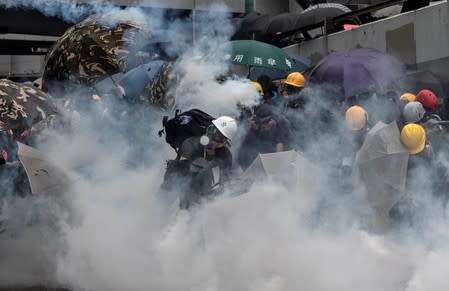 Demonstrators take cover as police fires tear gas during a protest in Hong Kong