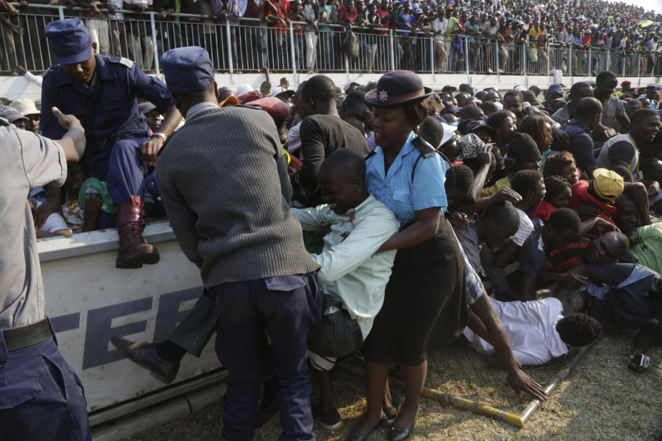 Injured mourners are helped after a stampede when mourners pushed and shoved after the arrival of the coffin carrying former President Robert Mugabe at the Rufaro Stadium in Harare, Thursday, Sept. 12, 2019 where Mugabe will lie in state for a public viewing. Mugabe, the founder leader, made his final journey back to the country Wednesday amid continuing controversy over where he will be buried. (AP Photo/Themba Hadebe)