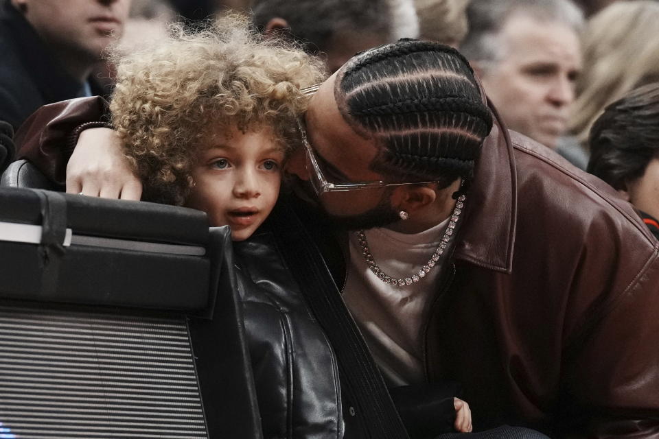 Drake sits with his son Adonis Graham as they watch the Toronto Raptors take on the Los Angeles Lakers during the first half of an NBA basketball game Wednesday, Dec. 7, 2022, in Toronto. (Chris Young/The Canadian Press via AP)