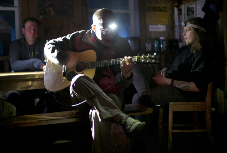 In this Friday, April 4, 2014 photo, hiker Joe Murdzek of East Hartford, Conn, sings and plays a guitar in the Gray Knob cabin in New Hampshire's Northern Presidential Range. Earlier in the day Murdzek and three friends climbed to the summit of Mount Adams, 1.6 miles above the cabin. (AP Photo/Robert F. Bukaty)