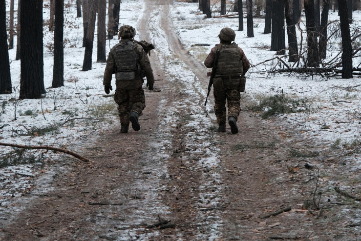 Members of Ukrainian military walk along a dirt road.