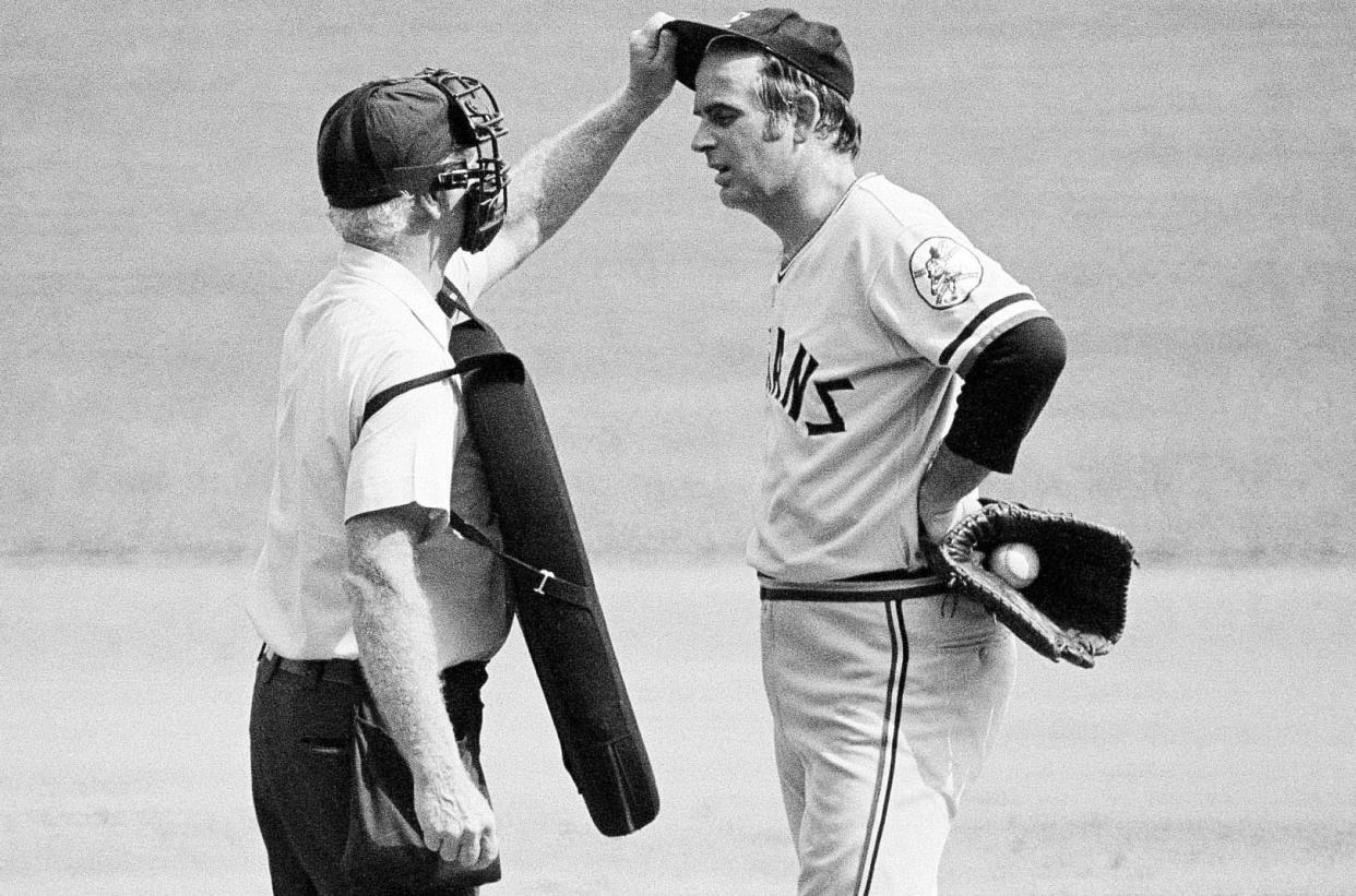 CORRECTS THAT PERRY WAS 84, NOT 88 AS ORIGINALLY SENT - FILE - Home plate umpire John Flaherty checks Cleveland Indians pitcher Gaylord Perry's cap for an illegal substance, at the request of Milwaukee Brewers manager Del Crandall, during the first game of a baseball doubleheader in Milwaukee, Sept. 3, 1973. Baseball Hall of Famer and two-time Cy Young winner Gaylord Perry, a master of the spitball, died Thursday, Dec. 1, 2022, at his home in Gaffney, S.C. He was 84. (AP Photo/File)