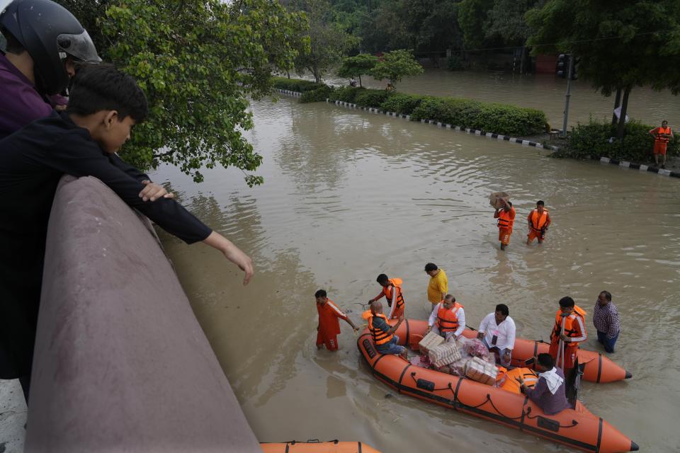 ARCHIVO - Personal de la Fuerza Nacional de Respuesta a Desastres de India distribuye material de ayuda a personas afectadas por las inundaciones cerca del río Yamuna en Nueva Delhi, India, el 14 de julio de 2023. (AP Foto/Manish Swarup, Archivo)