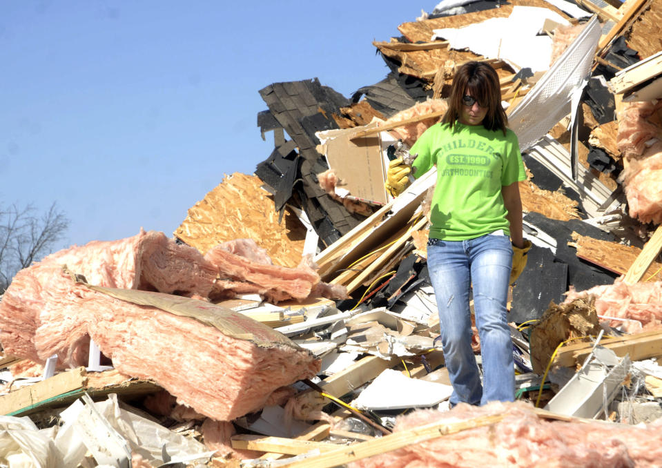 Cera Wise of Carrier Mill, Ill., searches for items in the rubble of a house that had blown across the road during Wednesday's tornado on Thursday, March 1, in Harrisburg, Ill. (AP Photo/The Southern Illinoisan, Paul Newton)