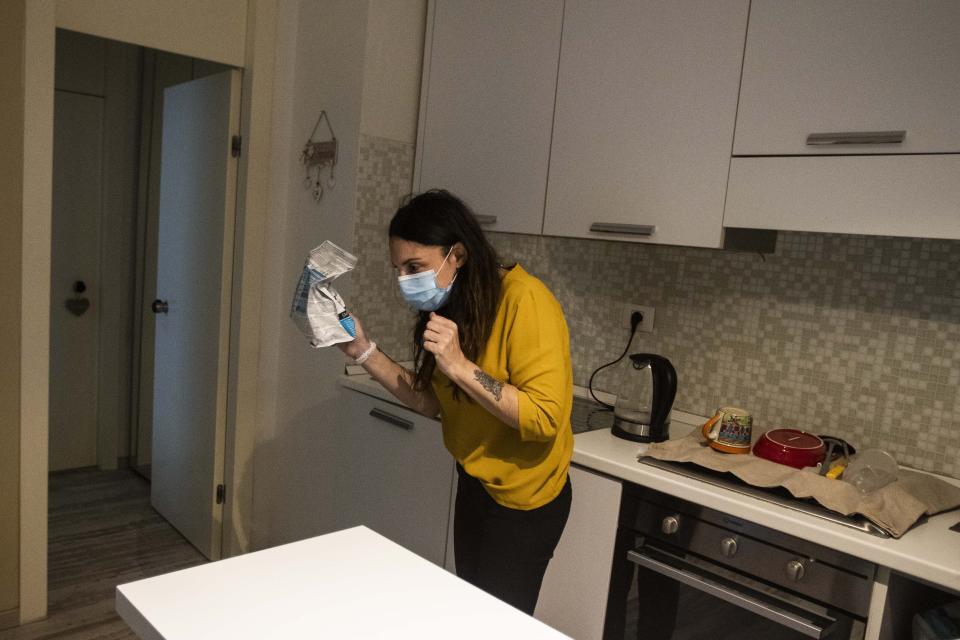 In this photo taken on Friday, April 10, 2020 nurse Cristina Settembrese shows a pack of food to her pet chihuahua dog Pepe at her home in Basiglio, Italy before going to Milan's San Paolo Hospital for her work shift. (AP Photo/Luca Bruno)
