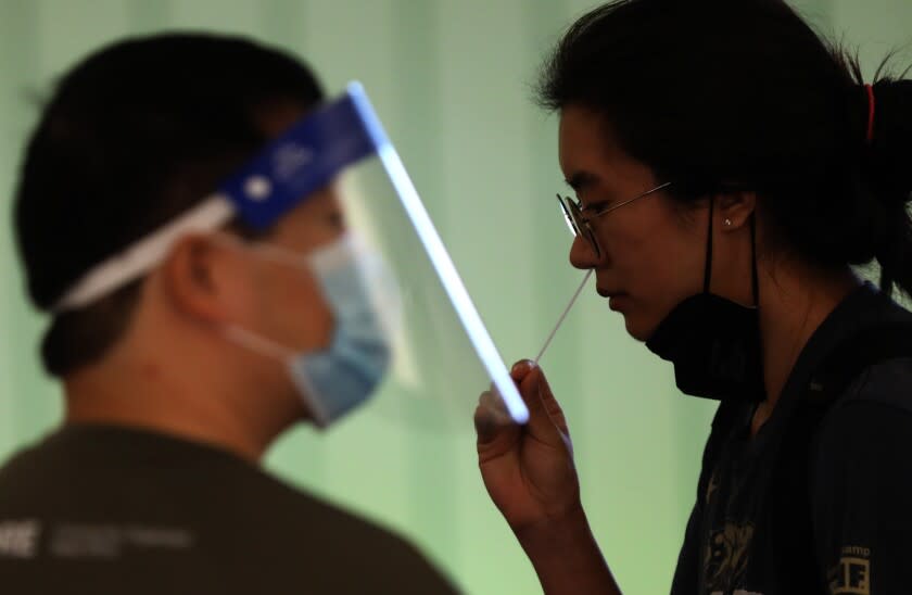 LOS ANGELES, CA - DECEMBER 3, 2021 - An arriving traveler takes a free COVID-19 Rapid Test under the direction of a CORE worker at the Tom Bradley International Terminal at Los Angeles International Airport Friday, December 3, 2021. In partnership with the state and U.S. Centers for Disease Control and Prevention, the county set up a free rapid testing site for arriving passengers. They were also gave those testing negative a kit they can use to test themselves again three to five days later, in line with CDC recommendations for international travelers coming to the U.S., regardless of vaccination status. (Genaro Molina / Los Angeles Times)