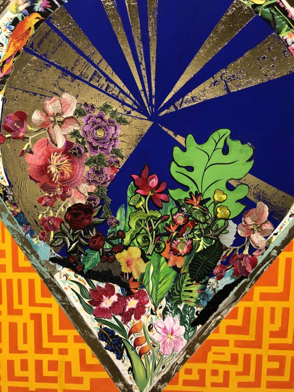 A detail of a painting by Carolyn Castaño shows lawyers of appliquéd tropical flowers emerging from painting with plants