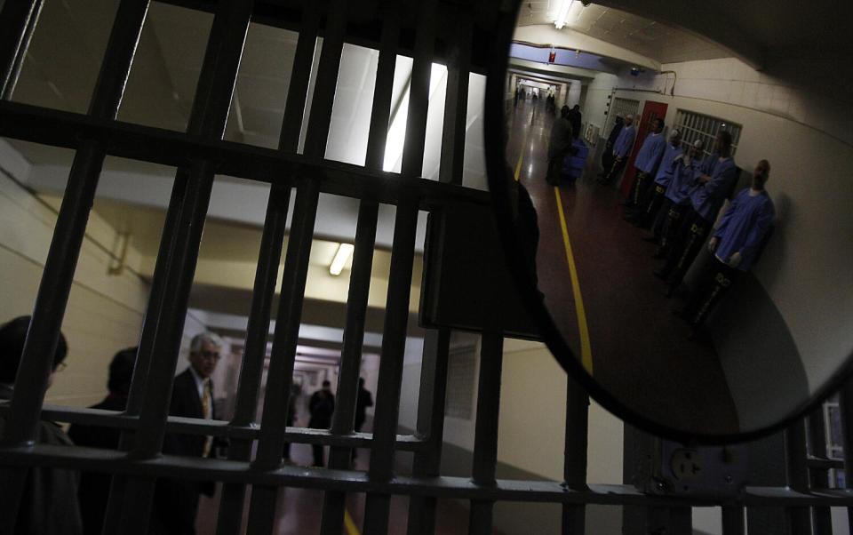 Inmates are reflected in a convex mirror affixed to iron bars at Deuel Vocational Institution in 2012.