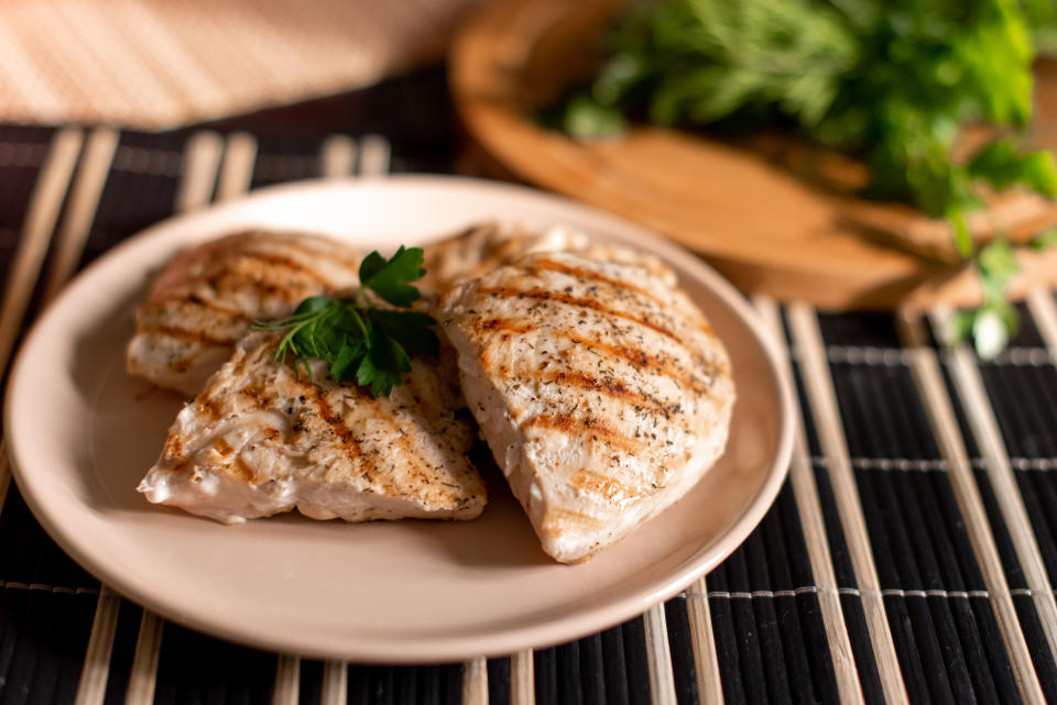 Grilled chicken breast in different variations with cherry tomatoes, green French beans, garlic, herbs, cut lemon on a teflon pan