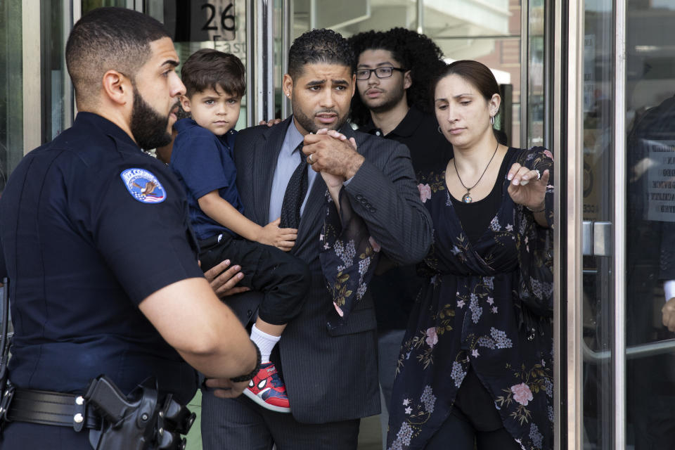 Juan Rodriguez, holding his son Tristan, leaves Bronx Criminal Court with his wife Marissa after a hearing, Thursday, Aug. 1, 2019 in New York. Rodriguez has pleaded not guilty to manslaughter and other charges in the deaths of their 1-year-old twins left in a car on Friday while he put in a day at work. Prosecutors say Rodriguez told police he thought he had dropped the twins off at day care.   (AP Photo/Mark Lennihan)