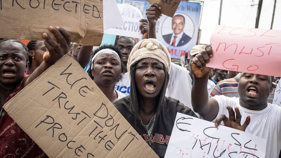 Hundreds of supporters of the opposition party, APC, hold up signs calling for the Chief electoral Commissioner, Mohamed Konneh, to step down after allegations of electoral fraud.  - John Wessels/AFP/Getty Images