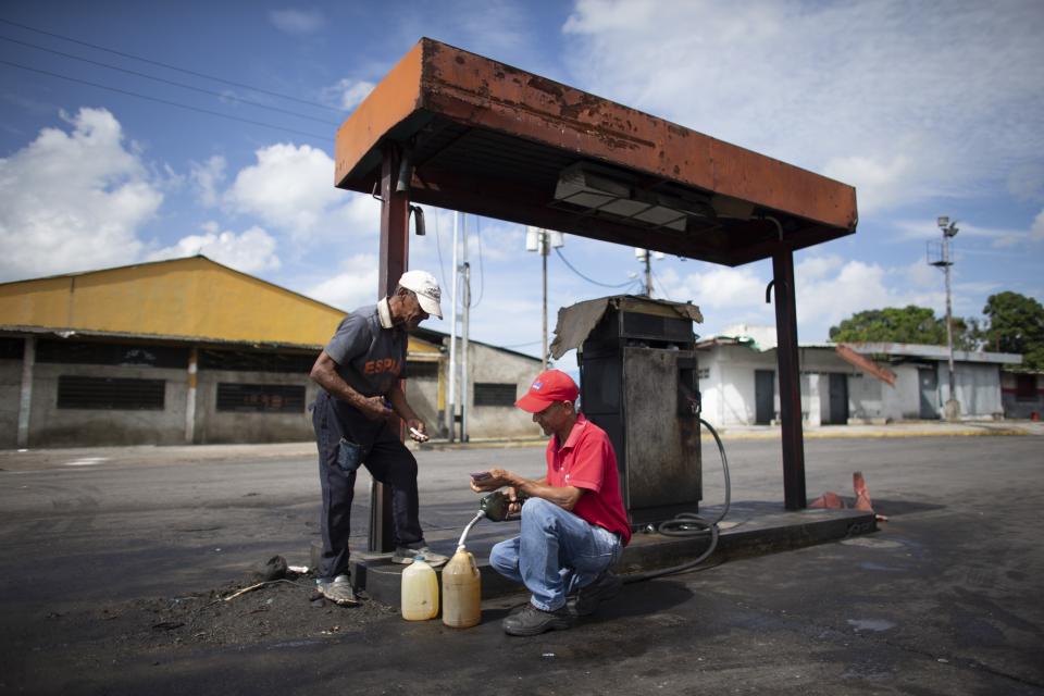 In this Oct. 13, 2019 photo, a gas attendant fills up plastic bottles with gasoline for a customer at a gas station in Chivacoa, Venezuela. Gas is so dirt-cheap that station attendants don’t even know the price, and empty handed drivers get waved through, paying nothing at all. (AP Photo/Ariana Cubillos)