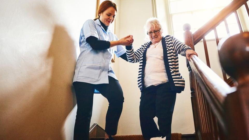 Mujer ayudando a anciana bajar escaleras