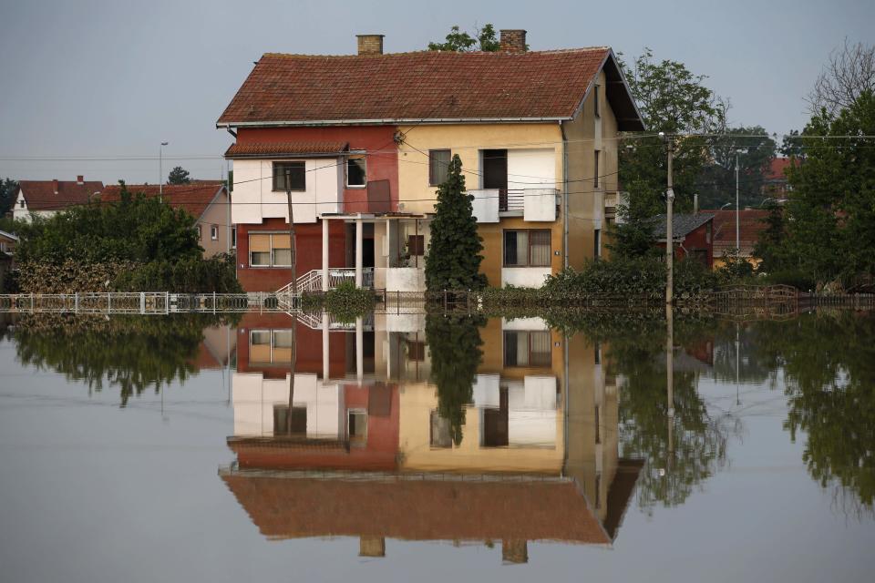 House is seen reflected in flood waters in Obrenovac