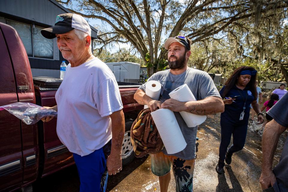 Brad Moore . right helps his father Felix Atkinson .left  carry out some of his belongings in a canoe from his flooded home in Peace River Village on the Peace River In Bartow Fl. Monday October 3,2022Ernst Peters/.The Ledger