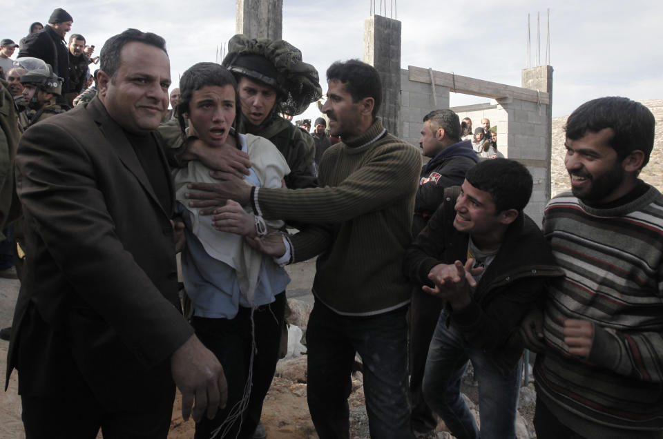 Two Palestinians (L and 4L) help an Israeli soldier evacuate an Israeli settler (2L) after he was detained and beaten by Palestinians from the village of Qusra in the  West Bank, on January 7, 2014. (JAAFAR ASHTIYEH/AFP/Getty Images)