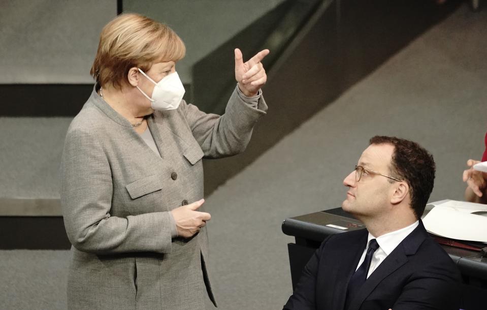 German Chancellor Angela Merkel, left, talks to German Health Minister Jens Spahn during a meeting of the German federal parliament, Bundestag, at the Reichstag building in Berlin, Germany, Wednesday, Nov. 8, 2020. German lawmakers attend a debate on a bill that will provide the legal underpinning for the government to issue social distancing rules, require masks in public and close stores and other venues to slow the spread of the virus. (Michael Kappeler/dpa via AP)