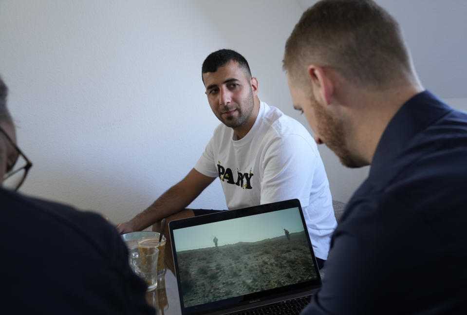 U.S. Army veteran Spencer Sullivan, right, and Abdulhaq Sodais, who served as a translator in Afghanistan, center, talk at Sodais' apartment in Bremen, Germany, Saturday, Aug. 14, 2021, while looking at video taken in Afghanistan. (AP Photo/Peter Dejong)