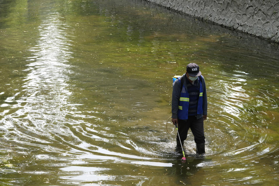 A worker wearing a mask disinfects a canal on Thursday, May 19, 2022, in Beijing. (AP Photo/Ng Han Guan)