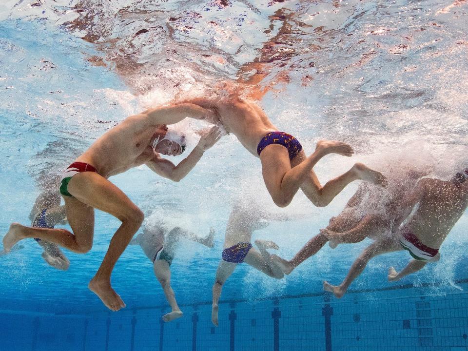 An underwater view of water polo players grappling at the Tokyo Olympics.