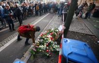 A woman lays flowers as people gather outside a kebab shop in Halle