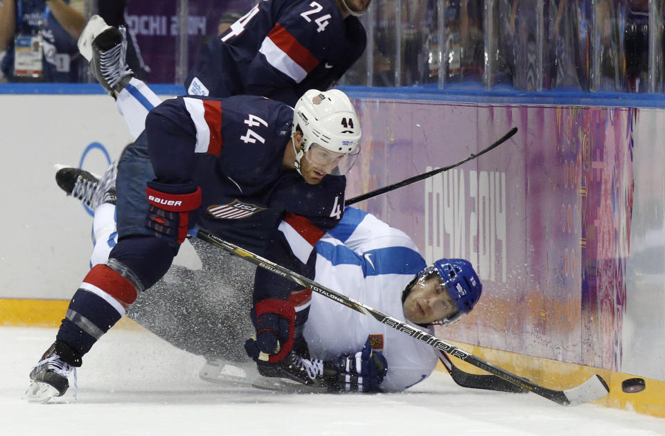 Finland forward Tuomo Ruutu hits the ice as he challenges USA defenseman Brooks Orpik for the puck during the second period of the men's bronze medal ice hockey game at the 2014 Winter Olympics, Saturday, Feb. 22, 2014, in Sochi, Russia. (AP Photo/Mark Humphrey)