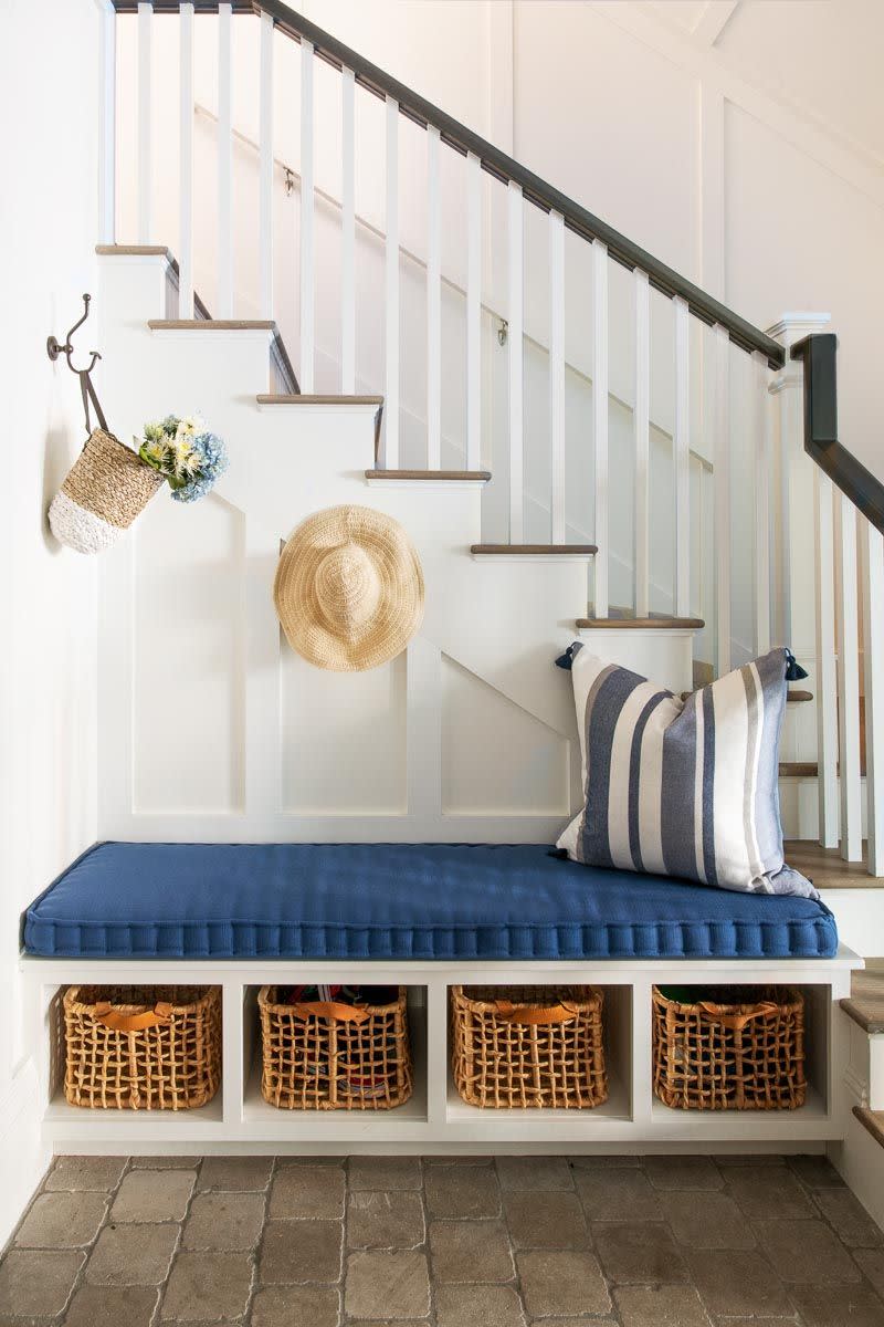a white staircase with a built in storage bench with baskets and pillow
