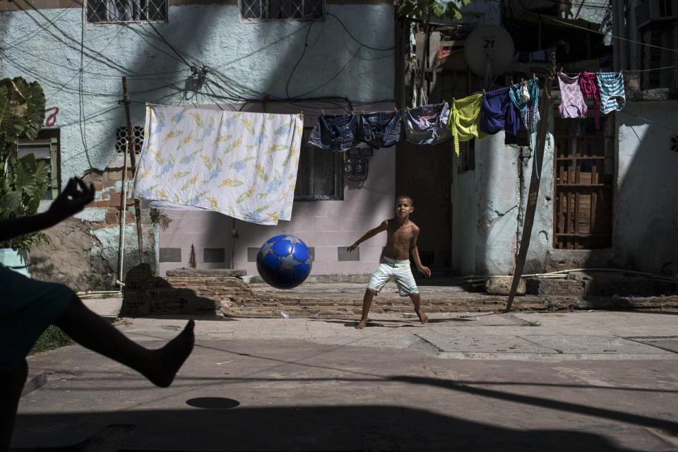 Igor Meireles, 8, center, plays goalkeeper as he prepares to block a kick from his brother Iago Meireles, 10, during their soccer game in the small square next to their home in Rio de Janeiro, Brazil, Sunday, March 16, 2014. The brothers took turns being the goalkeeper because neither wanted to play that position. With so many outstanding strikers and midfielders in Brazilian history, few chose goalkeepers as their childhood idols. (AP Photo/Felipe Dana)