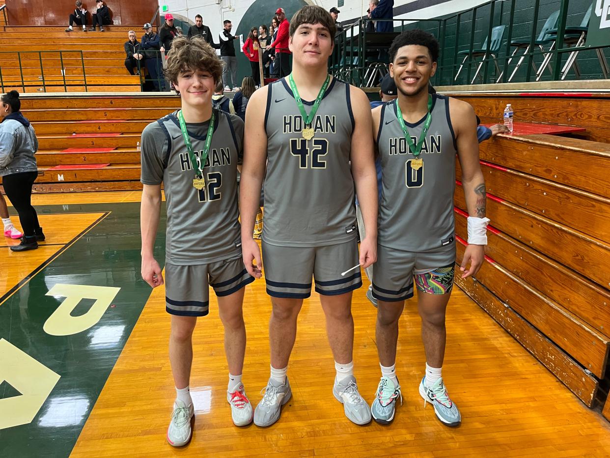 Archbishop Hoban boys basketball players, from left to right, James McCarthy, Sam Greer and Jonas Nichols smile with medals around their necks after winning a Division I district championship against Brecksville at the Elyria Catholic Coliseum on March 9, 2024.