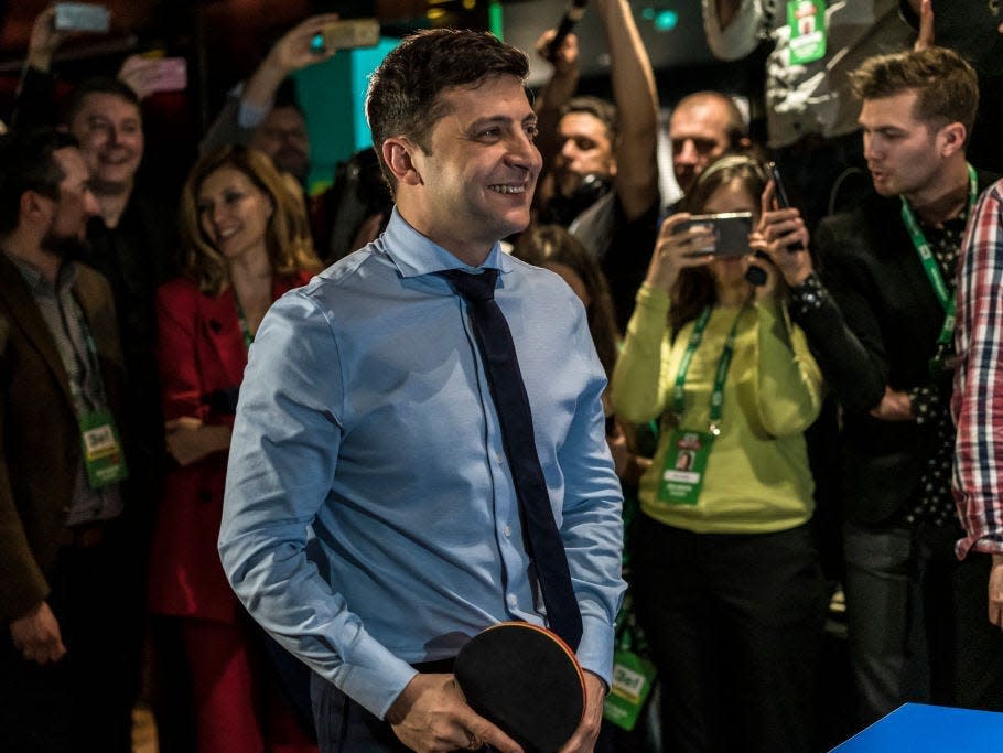 Volodymyr Zelensky plays ping pong as a crowd watches