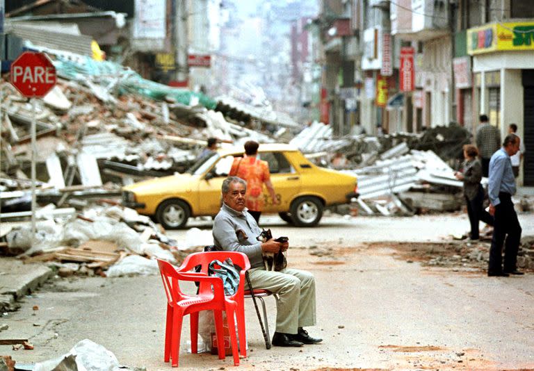 Un anciano, sosteniendo a su perro, toma un descanso en una calle central de Armenia, un día después del poderoso terremoto que midió 6.0 en la escala de Richter