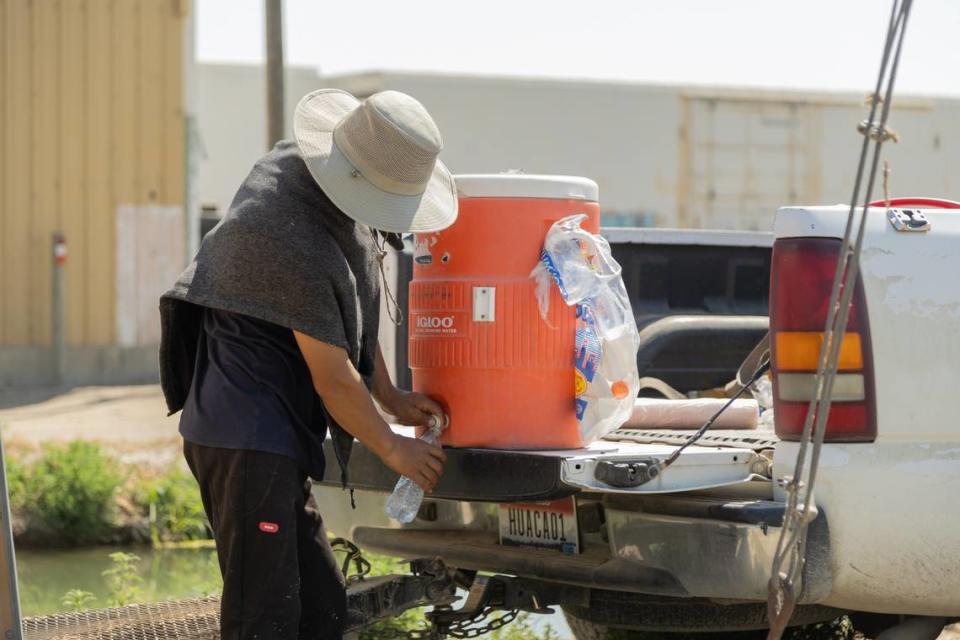 A farmworker filling his bottle with water while working in Wilder Daniel Ramirez