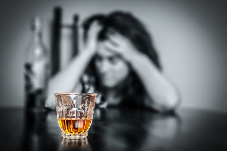 Out-of-focus woman with a glass of alcohol on the table in front of her