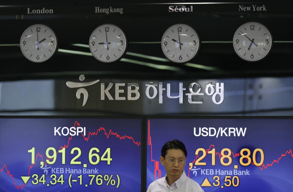 A currency trader walks by the screens showing the Korea Composite Stock Price Index (KOSPI), left, and the foreign exchange rate between U.S. dollar and South Korean won at the foreign exchange dealing room in Seoul, South Korea, Tuesday, Aug. 6, 2019. Asian stocks followed Wall Street lower on Tuesday after China let its currency sink and halted purchases of U.S. farm goods, fueling fears Beijing's trade war with President Donald Trump will harm the global economy. (AP Photo/Lee Jin-man)